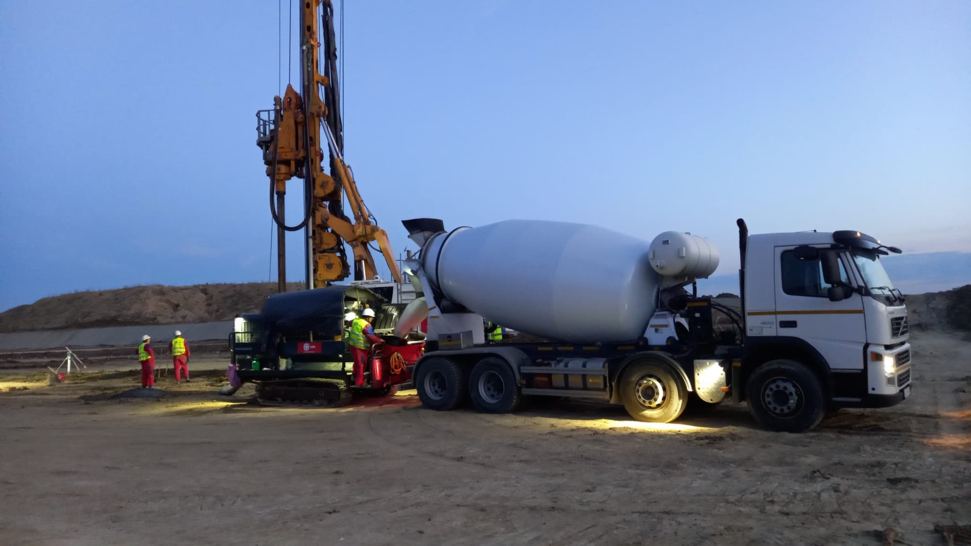 Autobetonieră AMI Beton și utilaje de pompare pe un șantier în Iași, la amurg